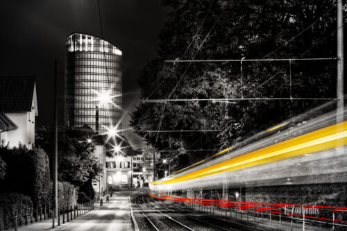 Schwarzweiss-Aufnahme mit roten und gelben Lichtschweifen einer vorbeirauschenden Straßenbahn in Stuttgart Vaihingen