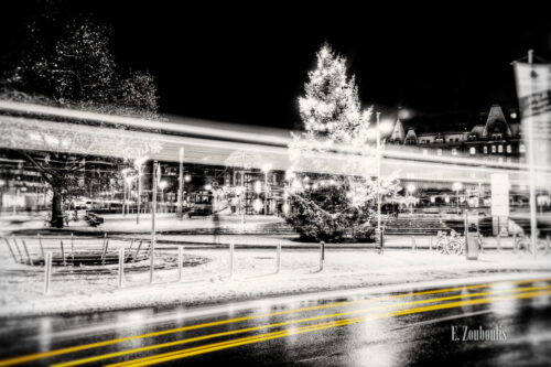 Schwarzweiß Aufnahme am Marienplatz in Stuttgart. Im Vordergrund ein gelber Lichtschweif, der den Verkehr kennzeichnet und im Hintergrund ein Weihnachtsbaum und die Zahnradbahn