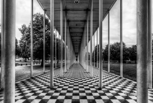 Schwarzweiß Aufnahme an der Wandelhalle in Böblingen. Im Vordergrund die schwarz/weißen Steine und die Säulenm die in die Mitte des Bildes zusammenlaufen