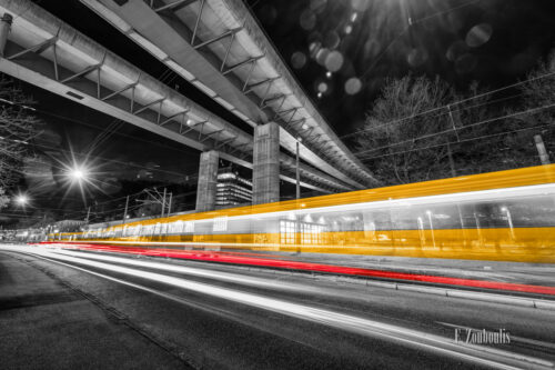 Schwarzweiß-Aufnahme am Straßenbahndepot in Stuttgart Vogelrain mit gelben und roten Lichtschweifen des vorbeifahrenden Verkehrs und der Straßenbahn